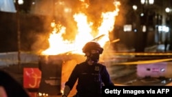 Police respond to a fire set by protesters following the police shooting of a man on April 17, 2021, in Portland, Oregon.