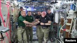 FILE - NASA astronauts Scott Kelly, right, and Tim Kopra shake hands as Kelly turns over command of the International Space Station to Kopra, Feb. 29, 2016.