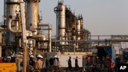 FILE - In this Sept. 20, 2019, file photo, taken during a trip organized by Saudi information ministry, workers fix the damage in Aramco's oil separator at processing facility after the recent Sept. 14 attack in Abqaiq, near Dammam in the Kingdom's…
