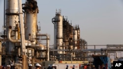 FILE - In this Sept. 20, 2019, file photo, taken during a trip organized by Saudi information ministry, workers fix the damage in Aramco's oil separator at processing facility after the recent Sept. 14 attack in Abqaiq, near Dammam in the Kingdom's…