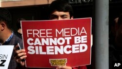 FILE - A protester is seen holding a placard at a rally in support of press freedom near the headquarters of a media company in Istanbul, Oct. 28, 2015.