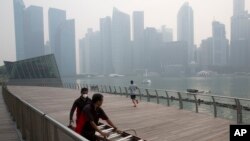 FILE - A worker wears a mask as he helps another push equipment during a hazy day in Singapore, Thursday, Sept. 10, 2015. 