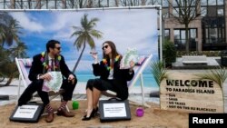 Activists stage a protest on a mock tropical island beach representing a tax haven outside a meeting of European Union finance ministers in Brussels, Belgium, Dec. 5, 2017. 