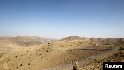 FILE - A soldier stands guard along the border fence outside the Kitton outpost on the border with Afghanistan in North Waziristan, Pakistan, Oct. 18, 2017.