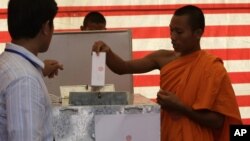 Cambodian Buddhist monk, right, casts his ballot in local elections at Wat Than pagoda's polling station in Phnom Penh, Cambodia, Sunday, June 3, 2012. 