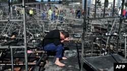 지난달 20일 그리스 북부 난민캠프에서 화재가 발생한 가운데 한 남성이 불에 탄 침대 위에서 머리를 숙이고 앉아있다. (자료사진)