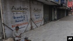 A Pakistani street vwndor sits next to a row of shuttered shops in a Karachi market after a week long period of violence in the city, March 31 2012.