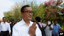 Cambodian main opposition Cambodia National Rescue Party leader Sam Rainsy, front, greets his supporters as his arrives at Choeung Ek memorial on the outskirts of Phnom Penh, Cambodia, Friday, May 17, 2015.