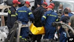 Firefighters remove a dead body that was killed in wildfires in Mati east of Athens, Tuesday, July 24, 2018.