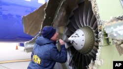 A National Transportation Safety Board investigator examines damage to the engine of the Southwest Airlines plane that made an emergency landing at Philadelphia International Airport in Philadelphia, April 17, 2018.