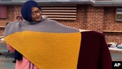 Aisha Bitini holds a handmade blanket she selected at a Welcome Blanket giveaway at the Association of Africans Living in Vermont on March 21, 2023, in Burlington, Vt. The blankets were to welcome refugees to the community. (AP Photo/Lisa Rathke)