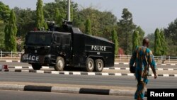 FILE - A man walks across the road toward a police water cannon truck following a government security alert in Abuja, Nigeria, Dec. 8, 2015.