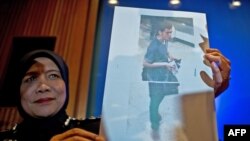 A Malaysian police official displays a photograph of 19-year-old Iranian Pouria Nour Mohammad Mehrdad, one of the two men who boarded missing Malaysia Airlines MH370 flight using stolen European passports to the media at a press conference near Kuala Lumpur International Airport in Sepang on March 11, 2014.