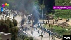 Gambar yang disiarkan oleh TV pemerintah menunjukkan bentrokan antara pasukan keamanan dan demonstran di kota Daraa, Jumat (8/4).