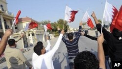 Anti-government protesters holding Bahraini flags walk in front of riot police during a protest held by al-Wefaq in Manama, January 7, 2012.