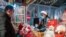 This photo taken Dec. 24, 2020, shows a vendor offering drinks to a customer at a Christmas-themed market outside of a shopping mall complex on Christmas Eve in Shanghai. 