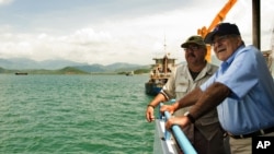 U.S. Secretary of Defense Leon Panetta, right, talks with Chief Mate Fred Cullen as he takes a boat out to a U.S. navy cargo ship USNS Richard E. Byrd in Cam Ranh Bay, Vietnam, June 3, 2012.