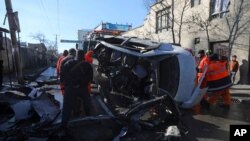 Afghan security personnel and municipality workers remove a damaged vehicle after a roadside bomb attack in Kabul, Dec. 22, 2020. 