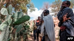 Orang-orang berkabung di depan kuburan massal para korban pembantaian yang diduga dilakukan oleh Tentara Eritrea yang bertetangga di desa Dengolat, Utara Mekele, ibu kota Tigray pada 26 Februari 2021. (Foto: AFP)