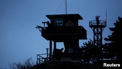 FILE - A South Korean soldier uses binoculars to look out to sea from a watchtower on Yeonpyeong island, which lies just inside the South Korean side of the Northern Limit Line, in the Yellow Sea, April 2014.