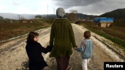 Siriyalik ayol farzandlari bilan Turkiya chegarasi yaqinidagi qochqinlar lagerida boshpana topgan. 