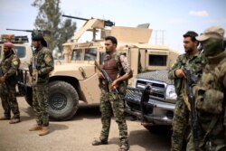 FILE - Fighters of Syrian Democratic Forces (SDF) stand guard in Deir Deir al-Zour, Syria, May 1, 2018.