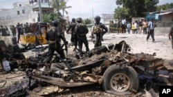 Tentara Somali berdiri dekat rongsokan mobil yang digunakan untuk bom bunuh diri di luar markas besar penyelidikan kejahatan di Mogadishu, Somalia, 31 Juli 2016.