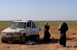 Dua wanita, istri seorang pejuang Negara Islam yang telah diidentifikasi sebagai warga negara Jerman, menunggu untuk diperiksa dan didaftarkan oleh Pasukan Demokrat Suriah, di pedesaan provinsi Deir Ezzor Suriah timur, 31 Januari 2019. (Foto: AFP )
