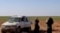 FILE - Two women, wives of an Islamic State fighter who has been identified as a German national, wait to be screened and registered by Syrian Democratic Forces, in the countryside of the eastern Syrian Deir Ezzor province, Jan. 31, 2019.