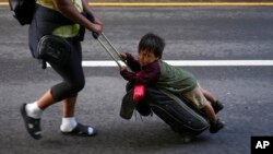 FILE - Nayely Nunez, from Honduras, uses her luggage to carry a child as she walks along the highway with a migrant caravan in Huixtla, southern Mexico, heading toward the country's northern border and ultimately the United States, Nov. 7, 2024.