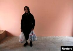 Cypriot Andrea Kyriakou, 81, carries bags of food distributed to her by the Orthodox church of Cyprus' community charity kitchen in Nicosia, Mar. 27, 2013.