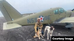 Pilot Eduard Seitan kneels in front of his plane with two rescue dogs on their way to their new "forever home." Seitan is a volunteer for the organization Pilots-n-Paws. 
