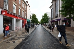 Shoppers wear face masks due to the novel coronavirus pandemic as they walk along the streets of Preston, Lancashire, Sept. 23, 2020.