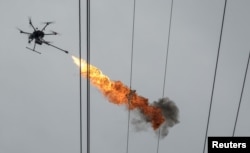 FILE - A drone emits flame to burn down trash from power lines, in Haikou, Hainan province, China, Nov. 16, 2017.