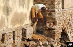 FILE - A low-caste sweeper cleans excreta flowing out of a public toilet at Ajmer, India.