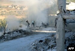 FILE - Syrians use dirt to put out a fire at the scene of a reported airstrike in the district of Jisr al-Shughur, in the Idlib province, Sept. 4, 2018.
