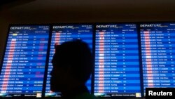 Seorang pria melintas di depan papan berisi jadwal penerbangan di Bandar Udara Internasional Kuala Lumpur 2 (KLIA2) di Sepang (30/4). (Reuters/Samsul Said)