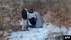A police officer stands next to Kai Zhuang at the site where he was found in the mountains near Brigham City, Utah, on Dec. 31, 2023, after being reported missing in an apparent cyber kidnapping scheme. (Riverdale Police Department via AFP)
