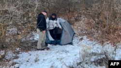 This handout photo released by the Riverdale Police Department on January 1, 2024 shows a police officer standing next with Kai Zhuang in the mountains near Brigham City, Utah, on December 31, 2023, after being reported missing. (Photo by Riverdale Police Department / AFP) 