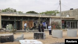 FILE - A man cleans his shop after a suicide car bomber blew himself up at a checkpoint in Dafniya outside Mistrata, Libya, May 31, 2015.