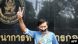 FILE - Thai journalist Pravit Rojanaphruk flashes a V-sign as he stands with his mouth taped outside a military base in Bangkok where he had been summoned by the junta, May 25, 2014.