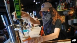 FILE - A bartender pours a beer for a customer at Shade Bar NYC in New York, June 22, 2020. 
