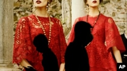 Dua pejalan kaki melintasi etalase sebuah butik pakaian ternama di Shanghai, China (Foto: dok). Shanghai telah menerapkan larangan terberat China terhadap kegiatan usaha pejabat pemerintah, dengan melarang pasangan mereka, anak-anak atau pasangan anak-anak mereka, menjalankan bisnis swasta di kota tersebut.