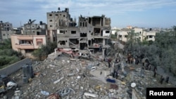 Warga Palestina berkumpul di lokasi serangan Israel terhadap rumah-rumah, di tengah konflik yang sedang berlangsung antara Israel dan kelompok Islam Palestina Hamas, di Kamp Maghazi di Jalur Gaza tengah, 25 Desember 2023. (Foto: REUTERS/Shadi Tabatibi)