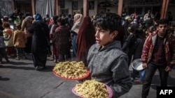 19일 가자지구 남부 라파의 학교에서 팔레스타인 피란민 어린이가 음식을 담은 접시들을 들고 있다.