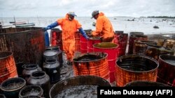 Des ouvriers ramassent des fuites de pétrole sur la plage de la Rivière des Créoles le 15 août 2020, en raison de la fuite de pétrole du navire MV Wakashio. (Photo by Fabien Dubessay / AFP)