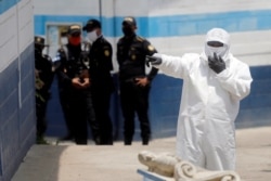 An employee of the Guatemala's Health Ministry, wearing a protective suit and a mask, gestures at a temporary shelter for Guatemalan migrants who arrived in the country on U.S. deportation flights, in Guatemala City, April 16, 2020.