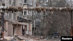 Seorang pria merokok di dekat gedung apartemennya yang rusak akibat serangan militer Rusia, di tengah serangan Rusia terhadap Ukraina, di kota garis depan Pokrovsk di wilayah Donetsk, Ukraina, 6 Maret 2025. (Foto: Inna Varenytsia/Reuters)
