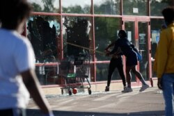A man breaks a window at a tire store, May 28, 2020, in St. Paul, Minnesota.