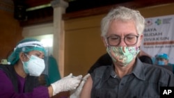 Seorang WNA divaksinasi COVID-19 dengan vaksin produksi AstraZeneca, saat pemerintah daerah Denpasar, Bali, menggelar vaksinasi massal, 22 Maret 2021. (AP Photo / Firdia Lisnawati).